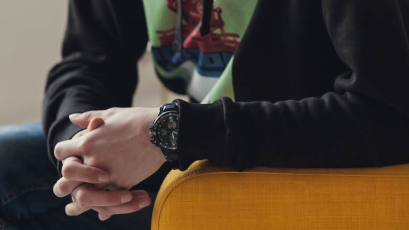 Detaljbild på en person med knutna händer som vilar på ett armstöd.