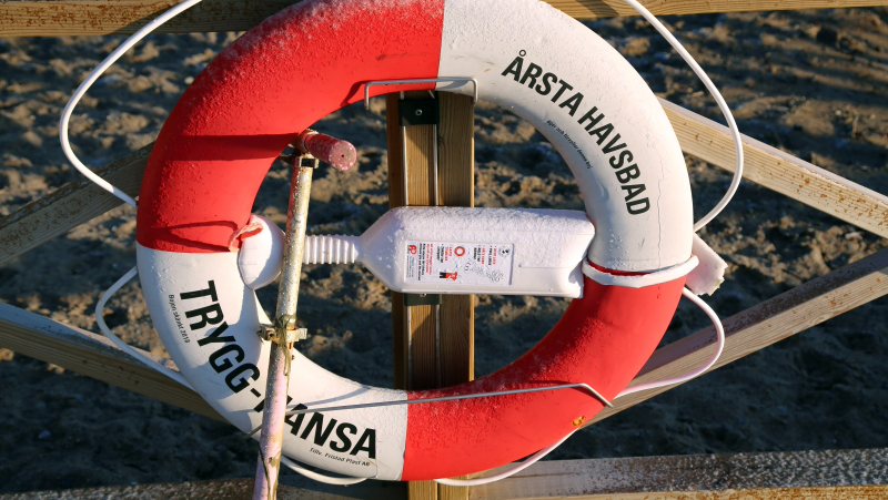 Livboj på brygga med texten Årsta havsbad och Trygg-Hansa.