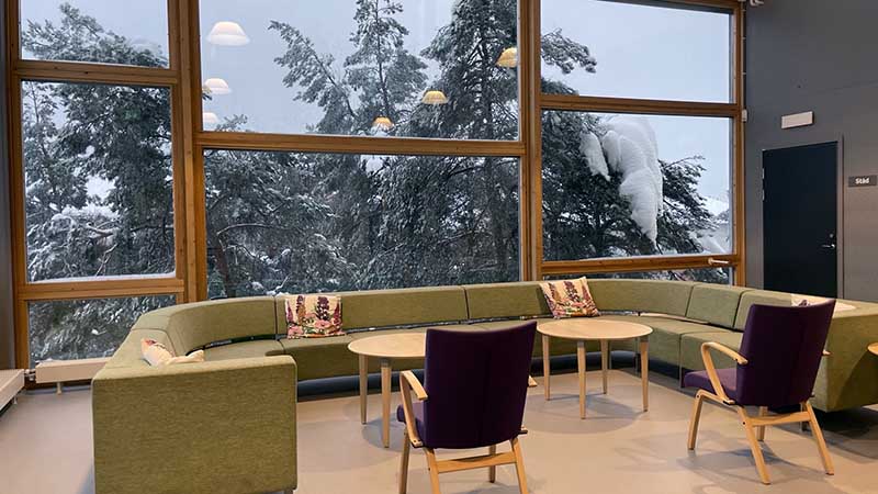 En soffa och fåtöljer framför ett stort fönster.