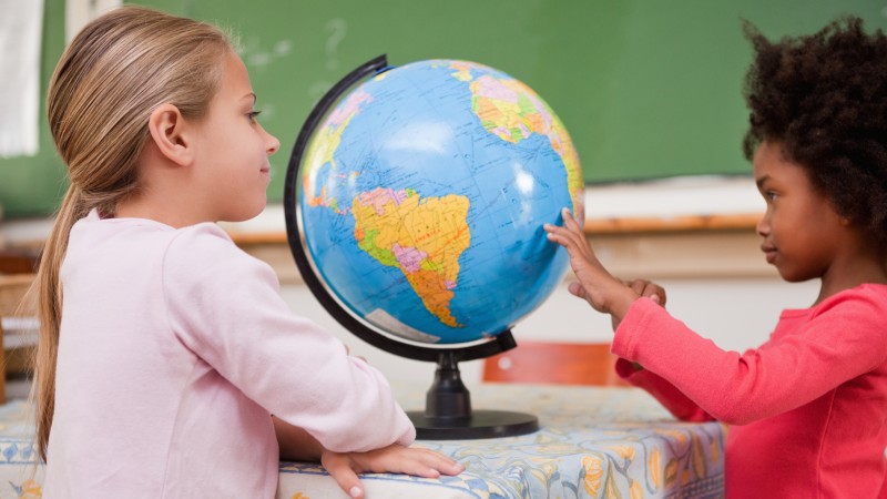 Två skolelever tittar på en jordglob.