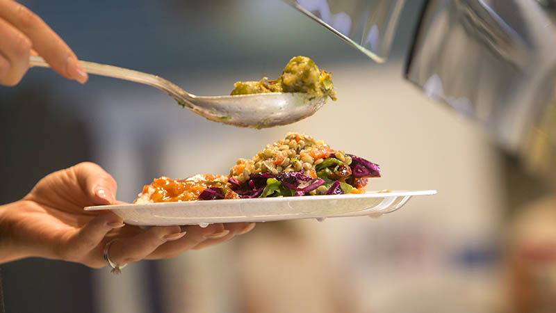 Någon tar mat från en buffé.