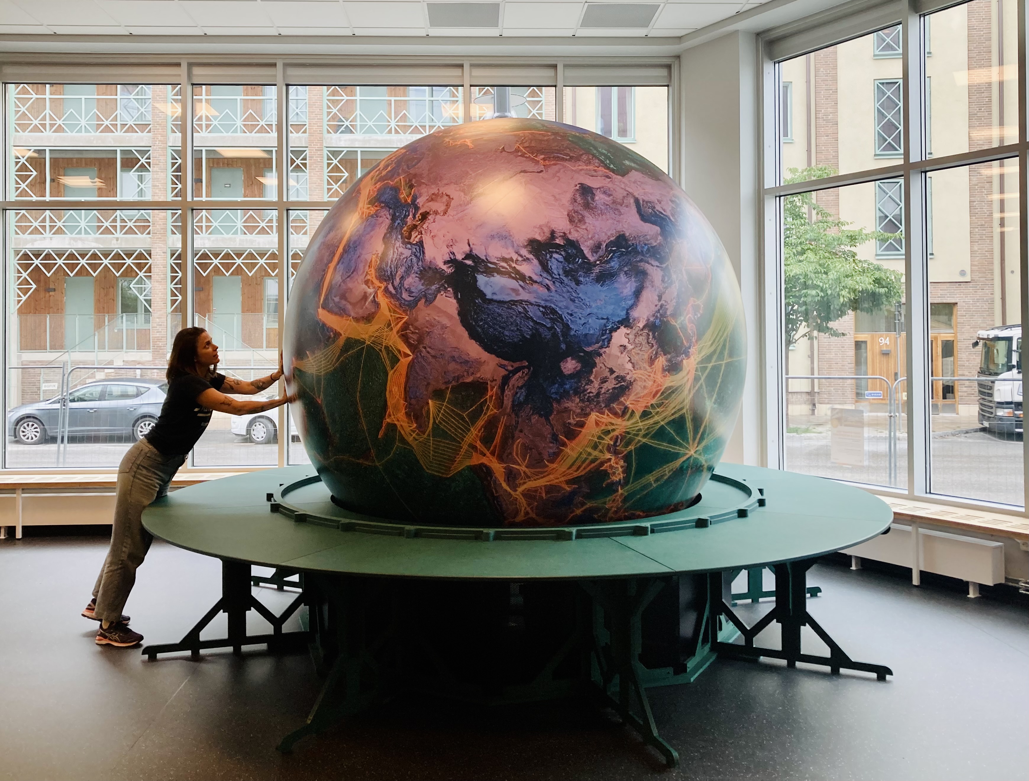 En flicka rör vid en stor glob.