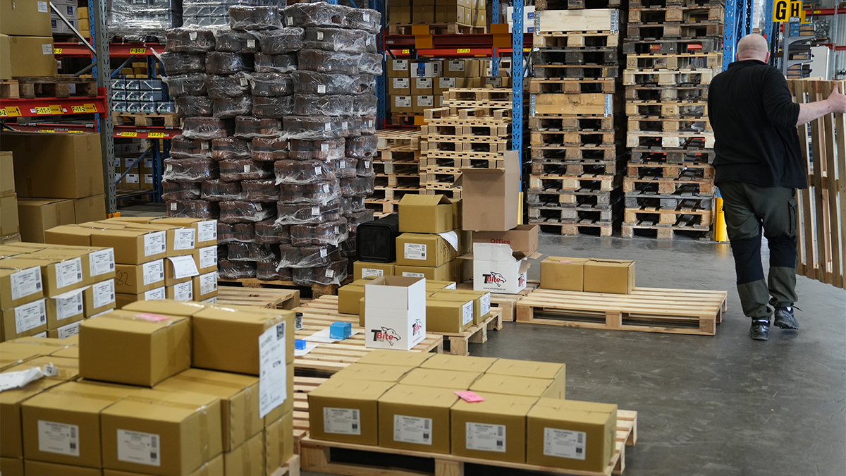 En lagerlokal och ryggen på en man som bär en packtrall. 