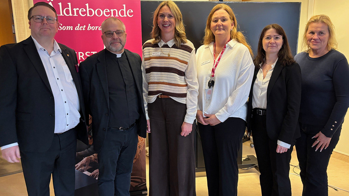 Sex personer vid en vägg. 