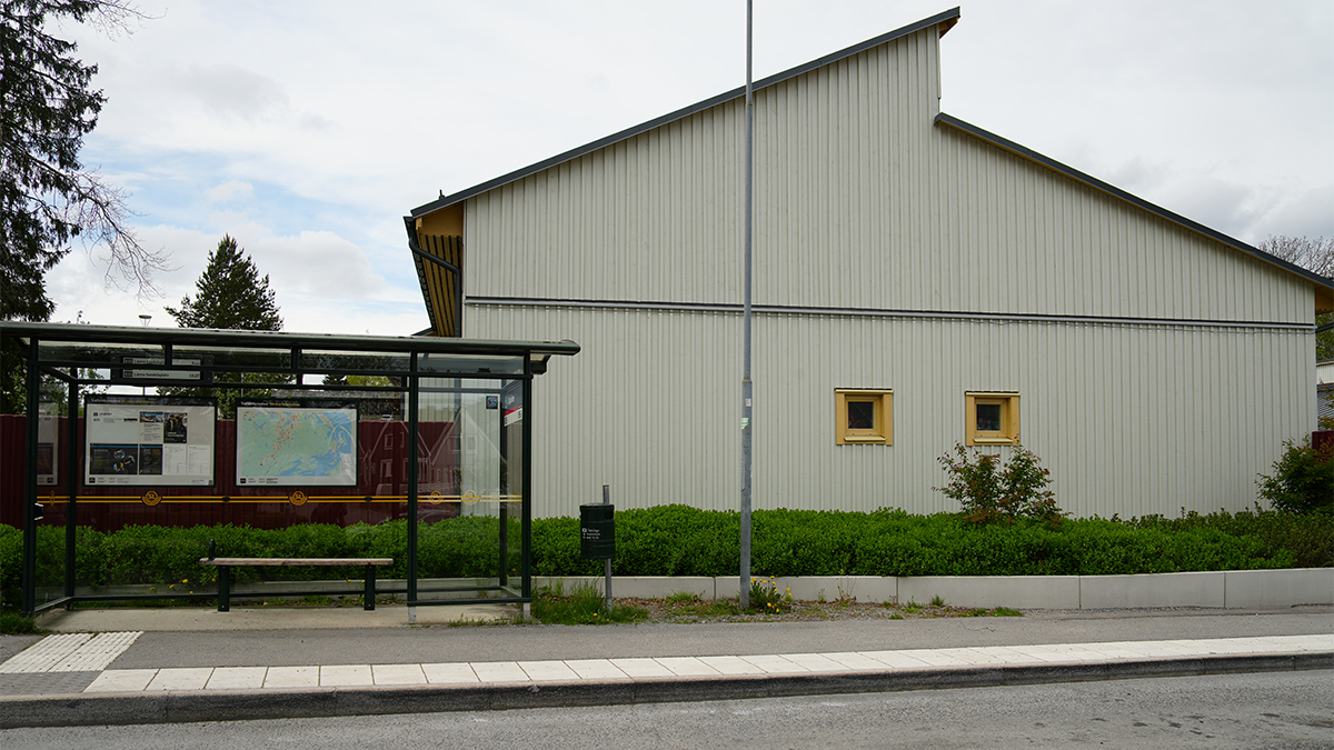 En busshållplats utanför ett vitt hus.
