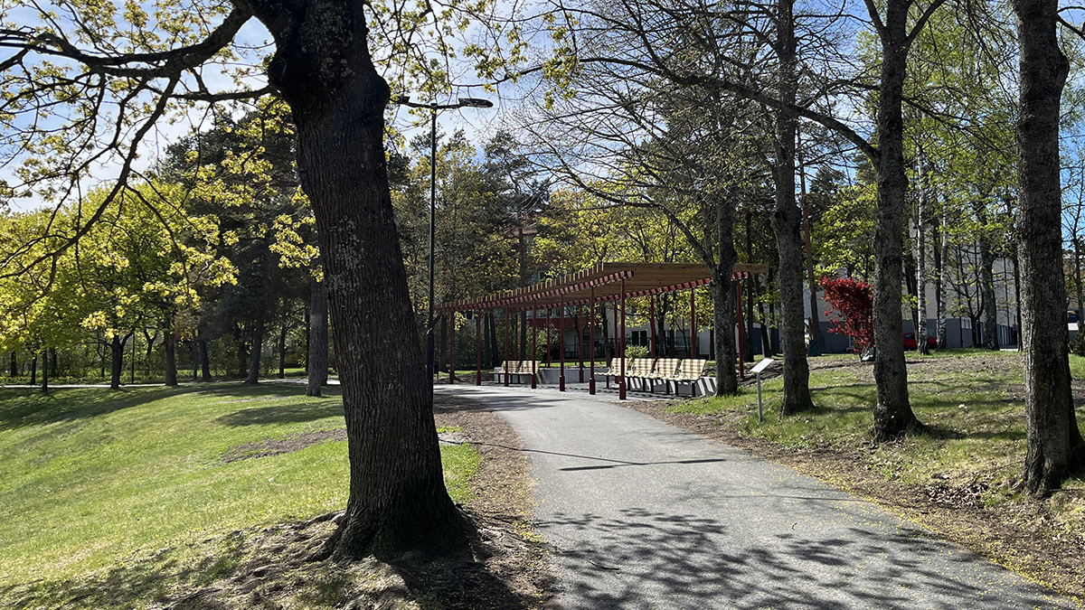 Pergola med sittplatser omgiven av plantering