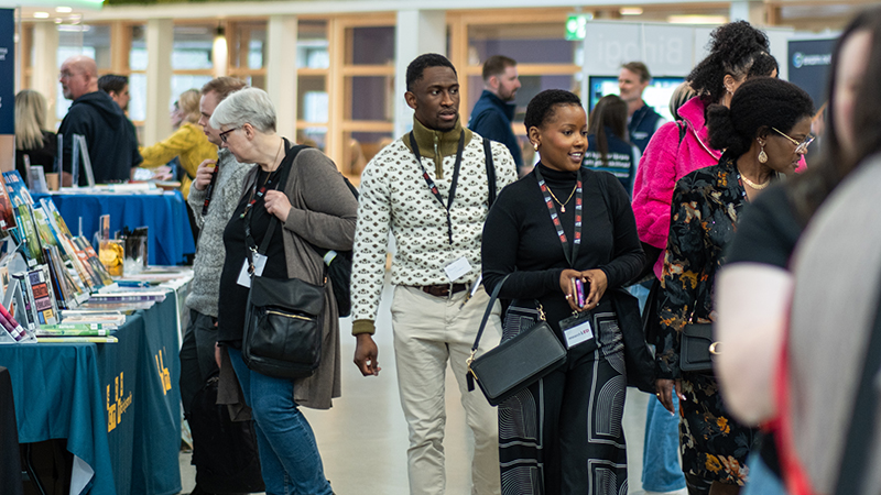 Flera människor minglar i en mässhall