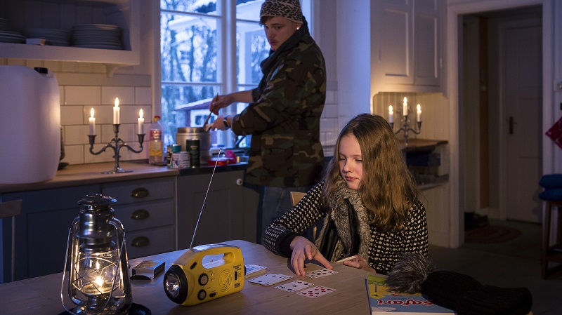 Två personer i ett mörkt kök med ficklampa och fotogenlykta.