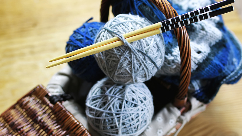 Garnnystan och stickor i en korg