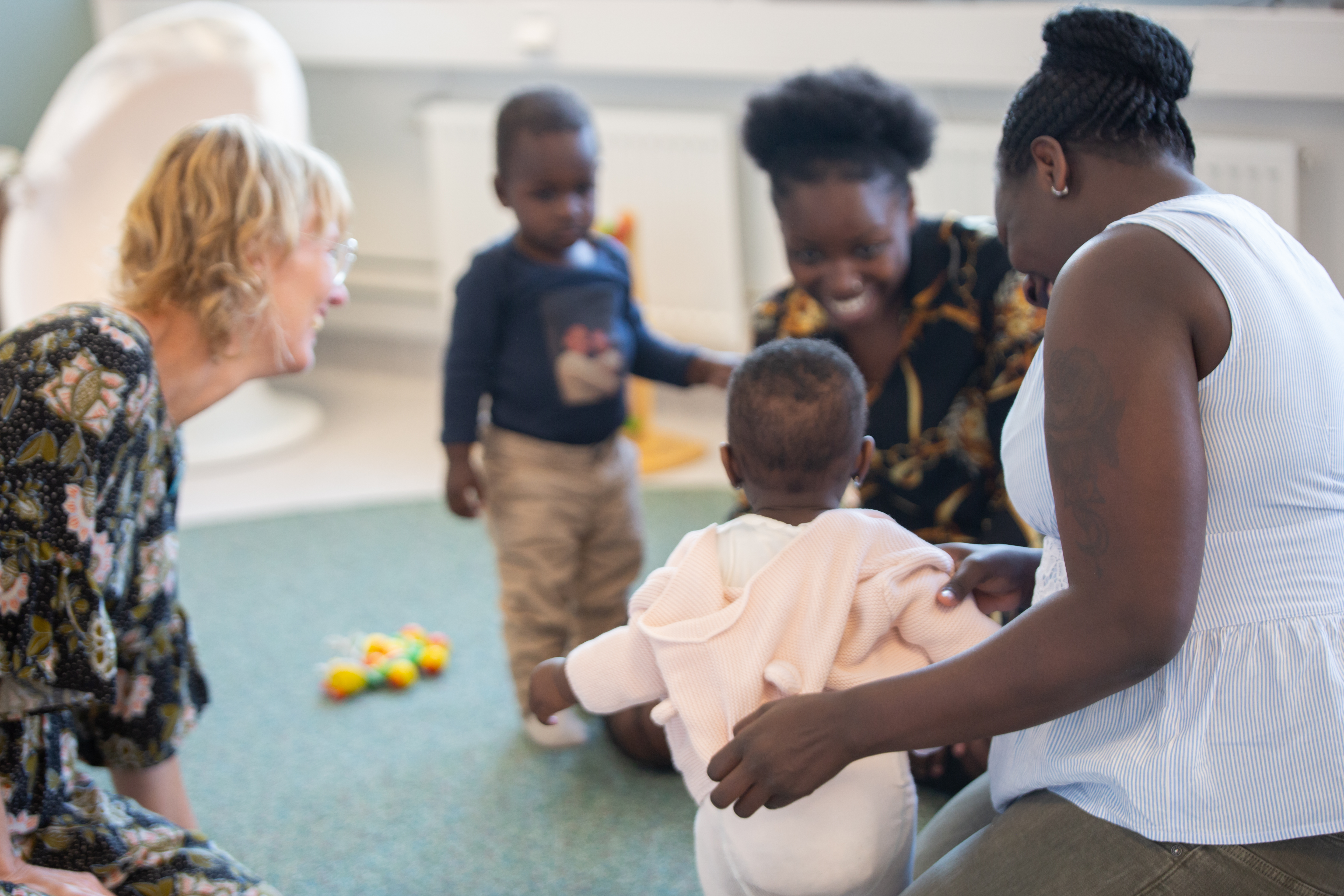 Personal sitter på golvet och leker med två familjer